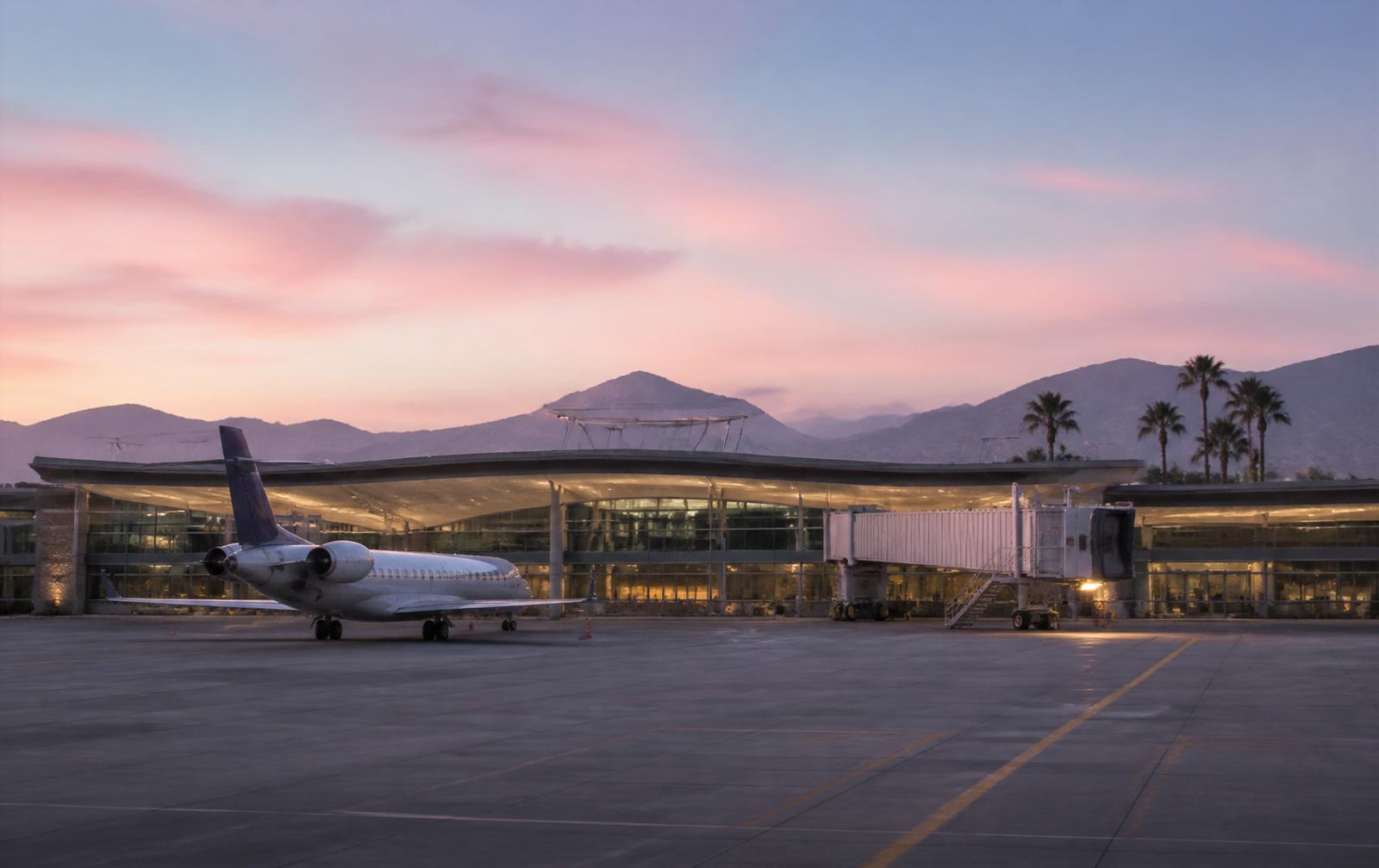 Quiet small regional airport terminal at dawn with a single aircraft parked and pastel mountains in the distance